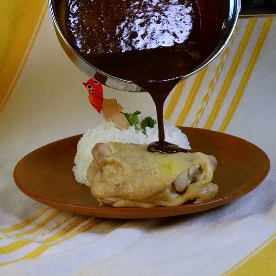 Mole poured over chicken and white rice, shown with mole negro